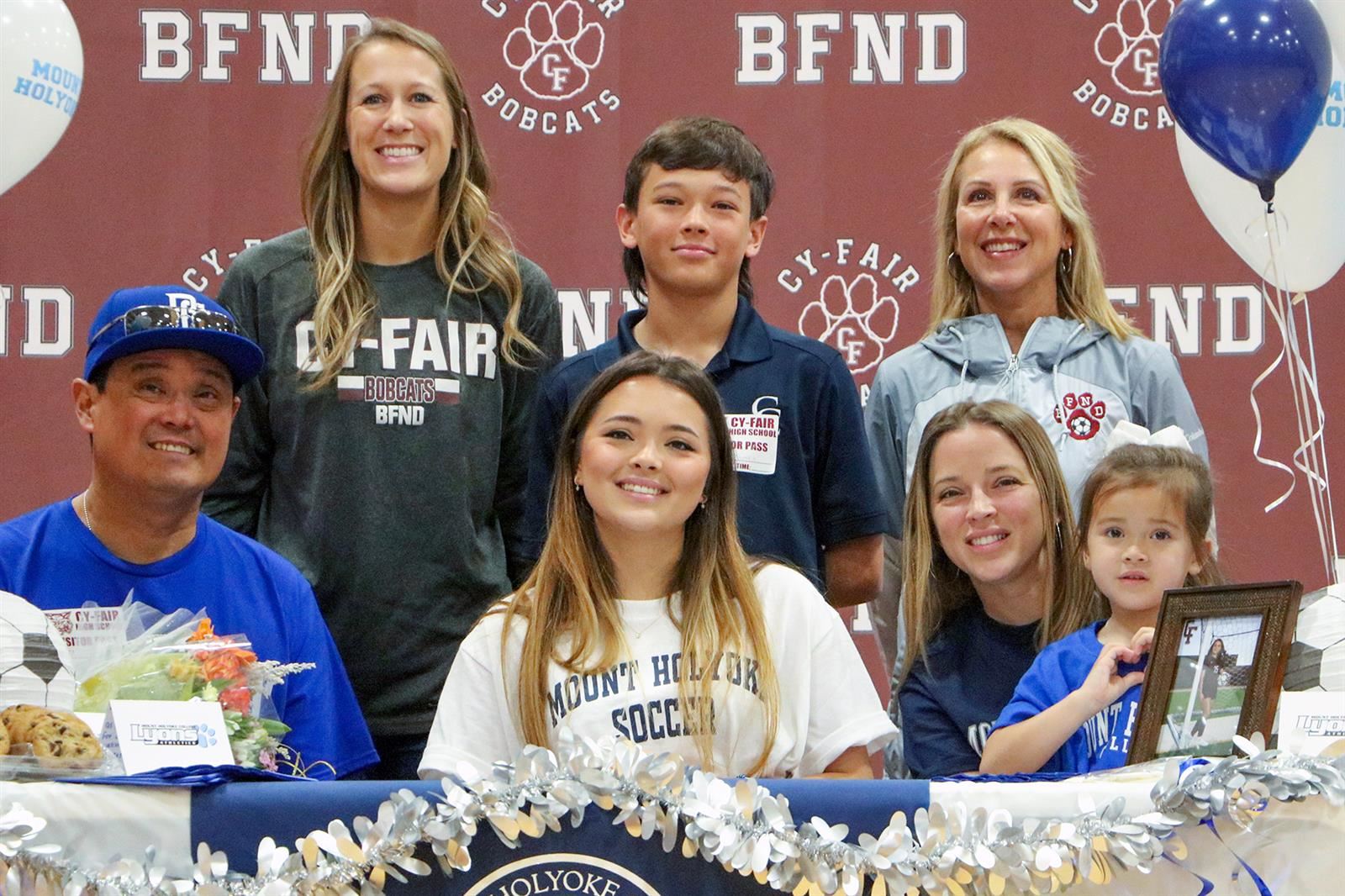 Cy-Fair High School senior Emily Tomita, seated center, poses with her family and coaches after signing a letter of intent.